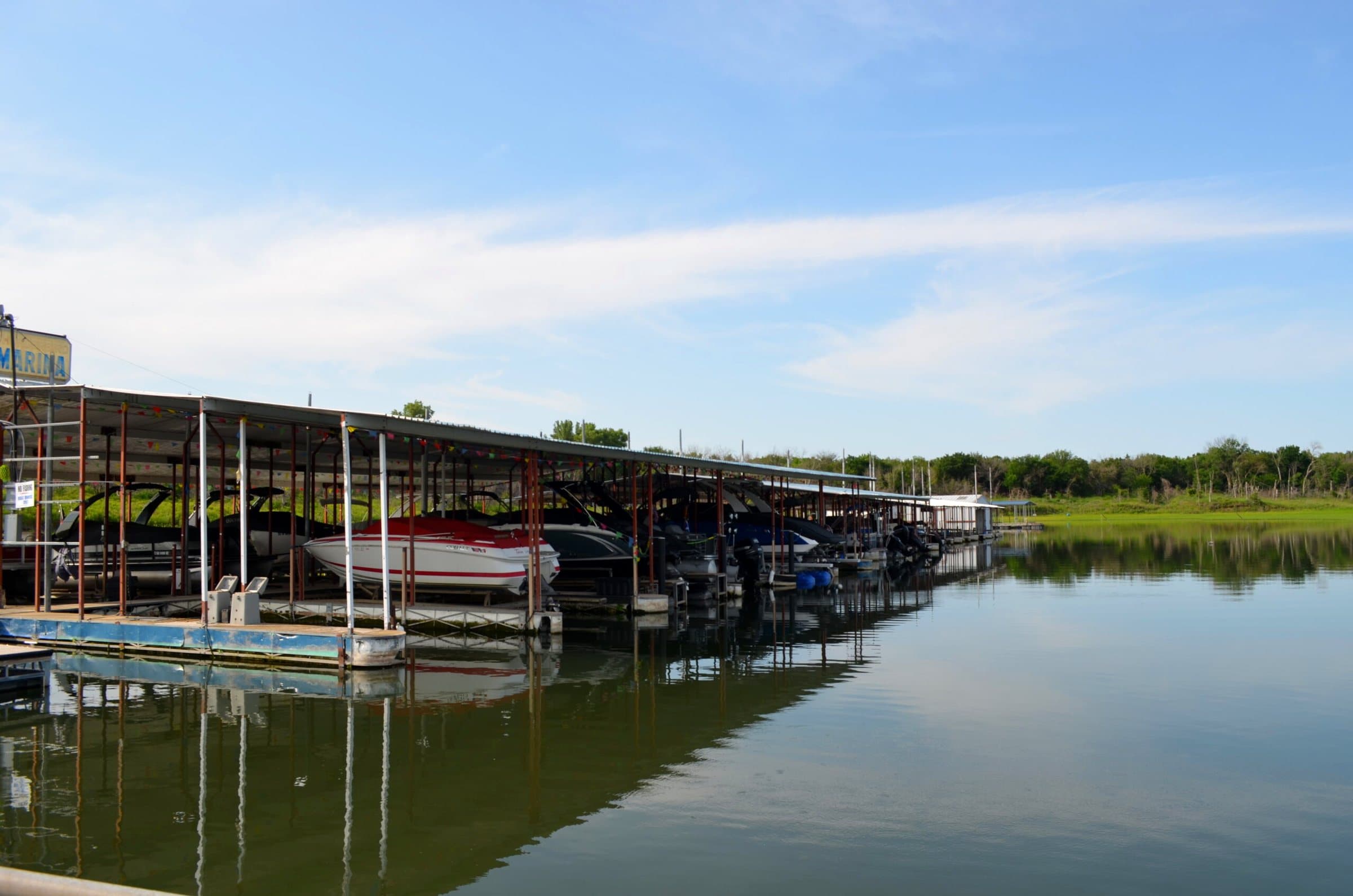 Covered boat slips with boats on lifts on glassy water