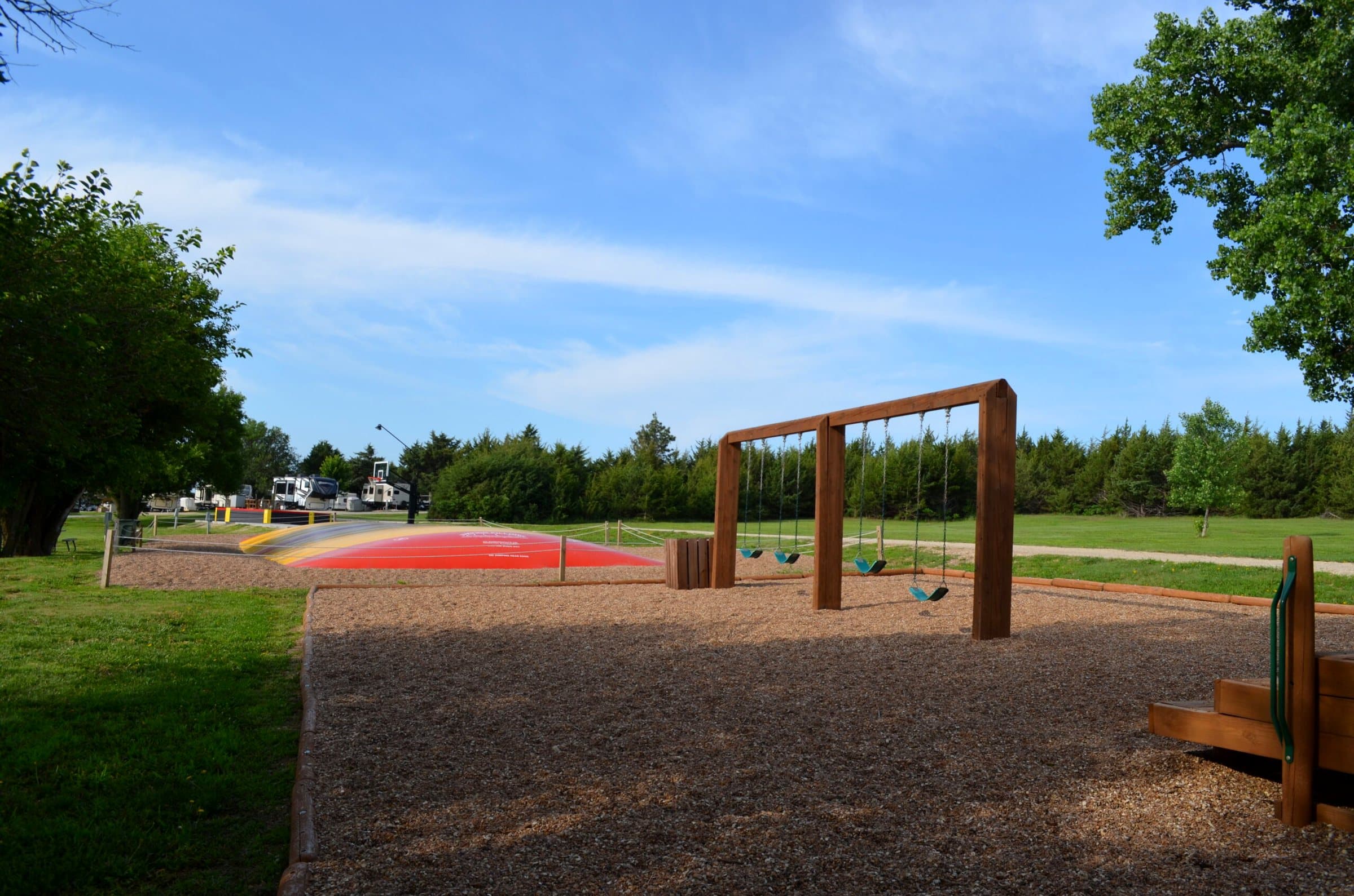 Red jumping pillow and swings at the playground